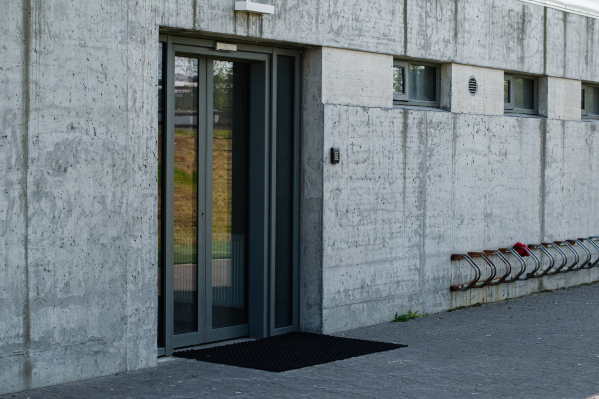 Concrete building with a glass door entry and bike rack in urban Mosfellsbær.